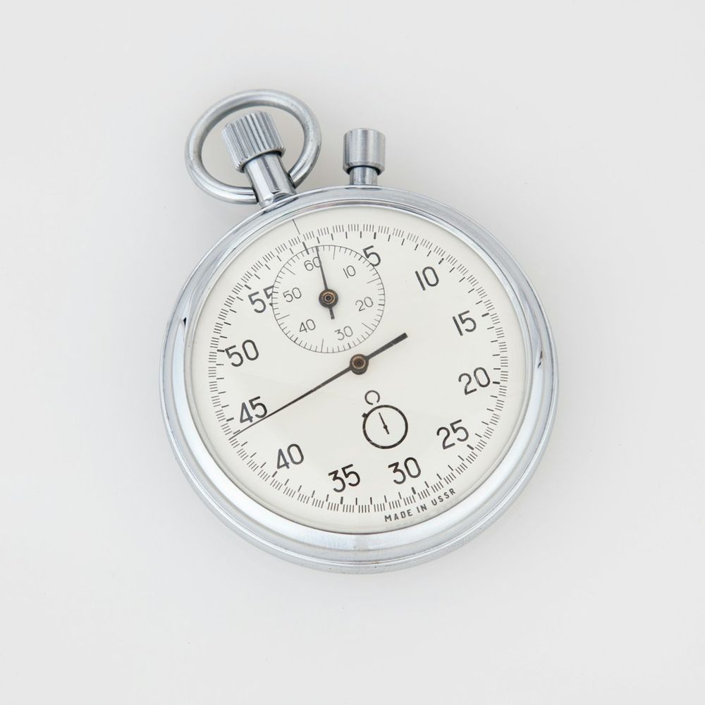 Silver analogue stopwatch with a white dial on a pale grey background