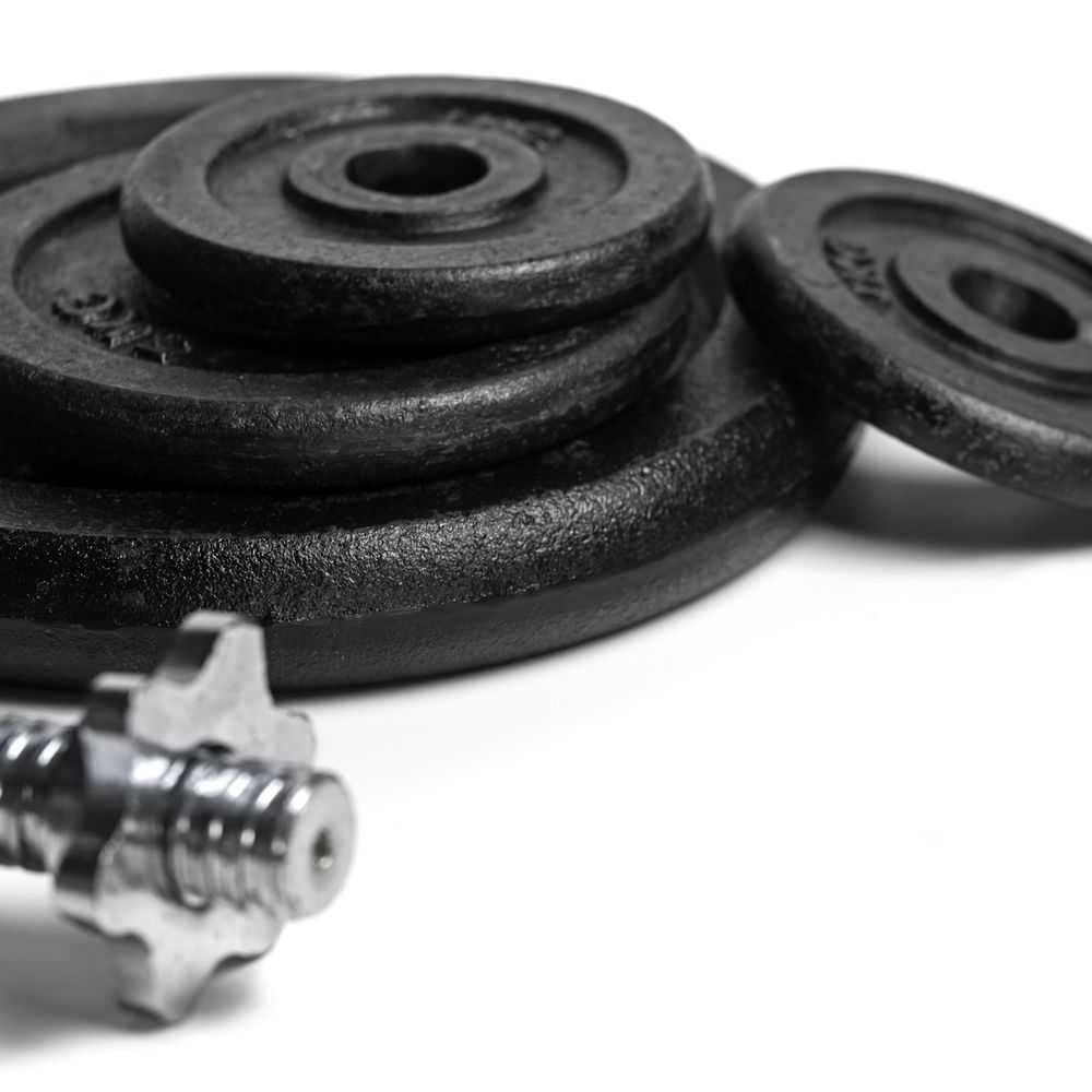 Stack of round black weight plates beside a chrome spin collar on a white background