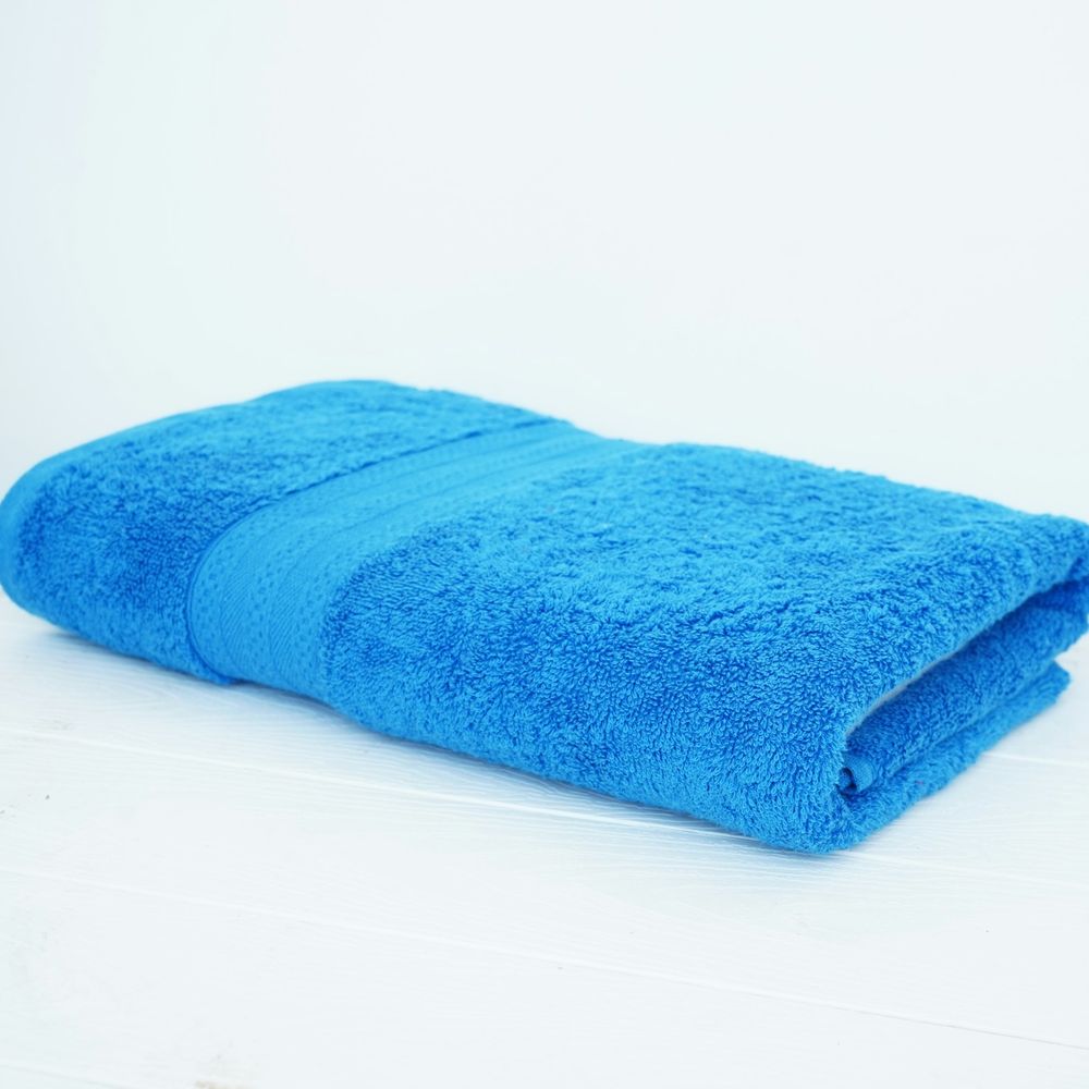 Folded bright blue terry-cloth towel on a white surface